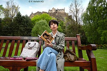 Sally Hawkins als Philippa Langley sitzt auf einer Bank unterhalb von Edingburgh Castle und liest Bücher über König Richard III.
