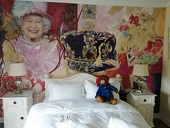 Der Queen's Room im Hotel The Little Britain Inn mit Wandgemälde, Doppelbett, Nachttischen und Paddington Bear als Stofftier