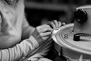 Nahaufnahme einer Mitarbeiterin von Fisherman out of Ireland, die händisch Strickarbeiten an einem Kleidungsstück ausführt.