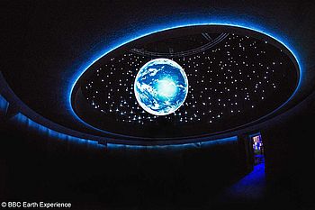 Ausstellungs-Installation mit einer illuminierten Weltkugel und dem Sternenhimmel
